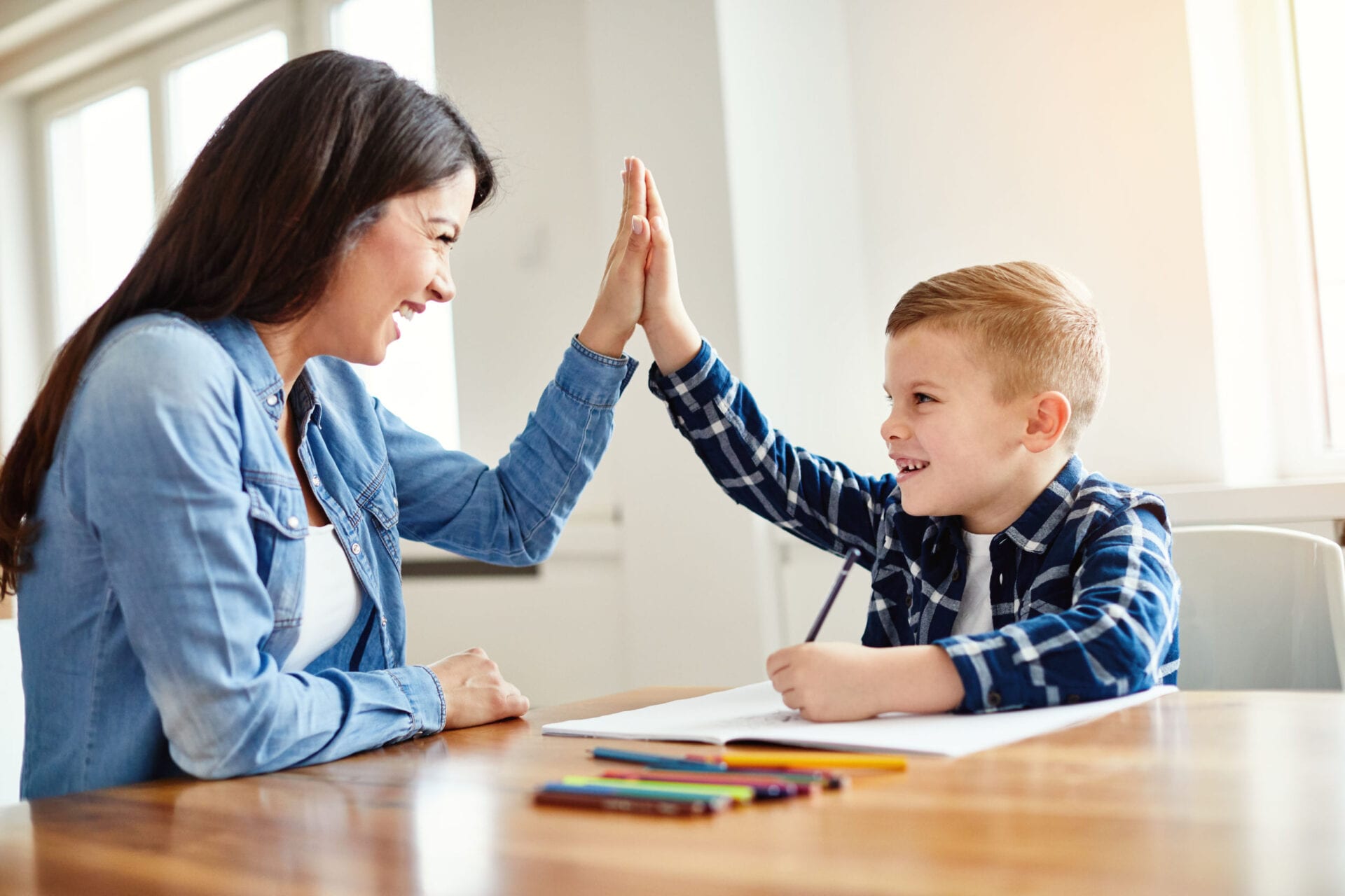 Teacher helping student with homework, celebrating with a high five